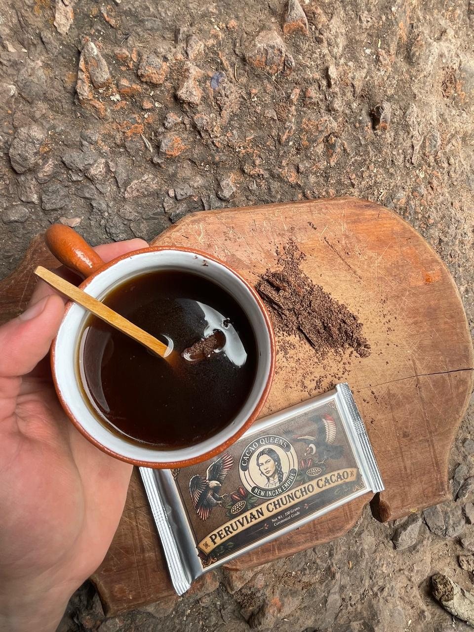 A hand holding a terracotta cup of 100% Chuncho cacao next to one of the bars.