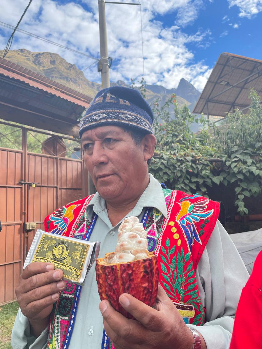 Austin's father-in-law in traditional Andean dress, holding an open cacao pod and a bar