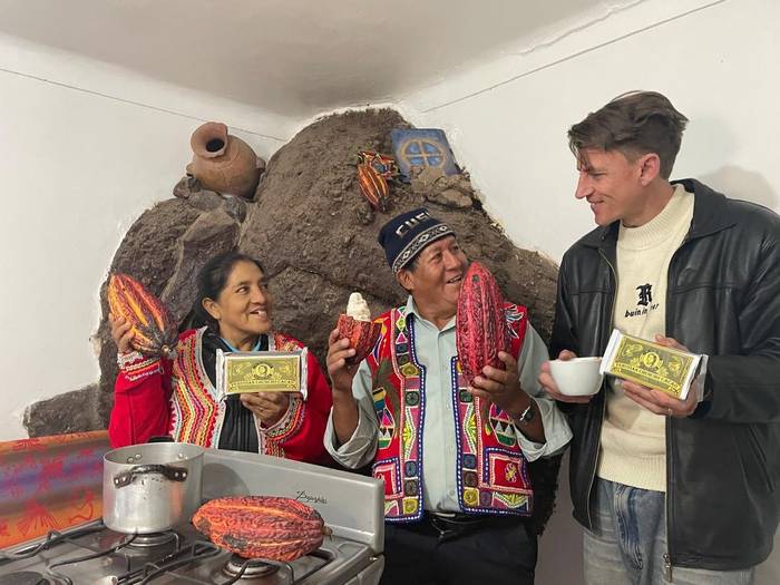 Austin in the kitchen in Cusco with his parents-in-law, holding cacao pods and a bar